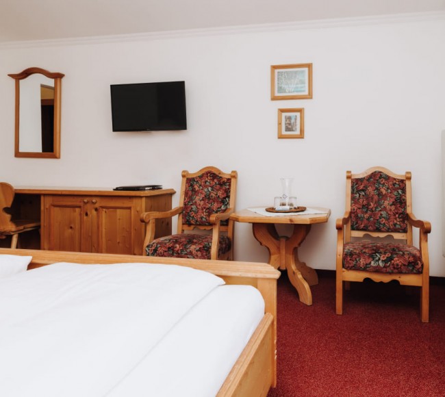 Zimmer mit TV und Sitzmöglichkeiten im Hotel Garni Tannenhof